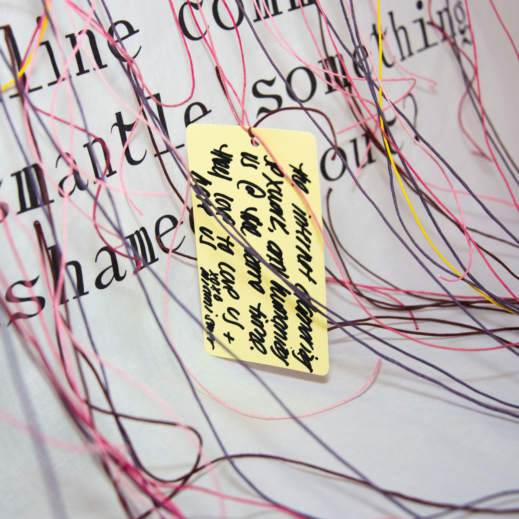 A closeup of the banner shows it's covered in draping colored strings, one with a yellow tag covered in handwriting tied to it.